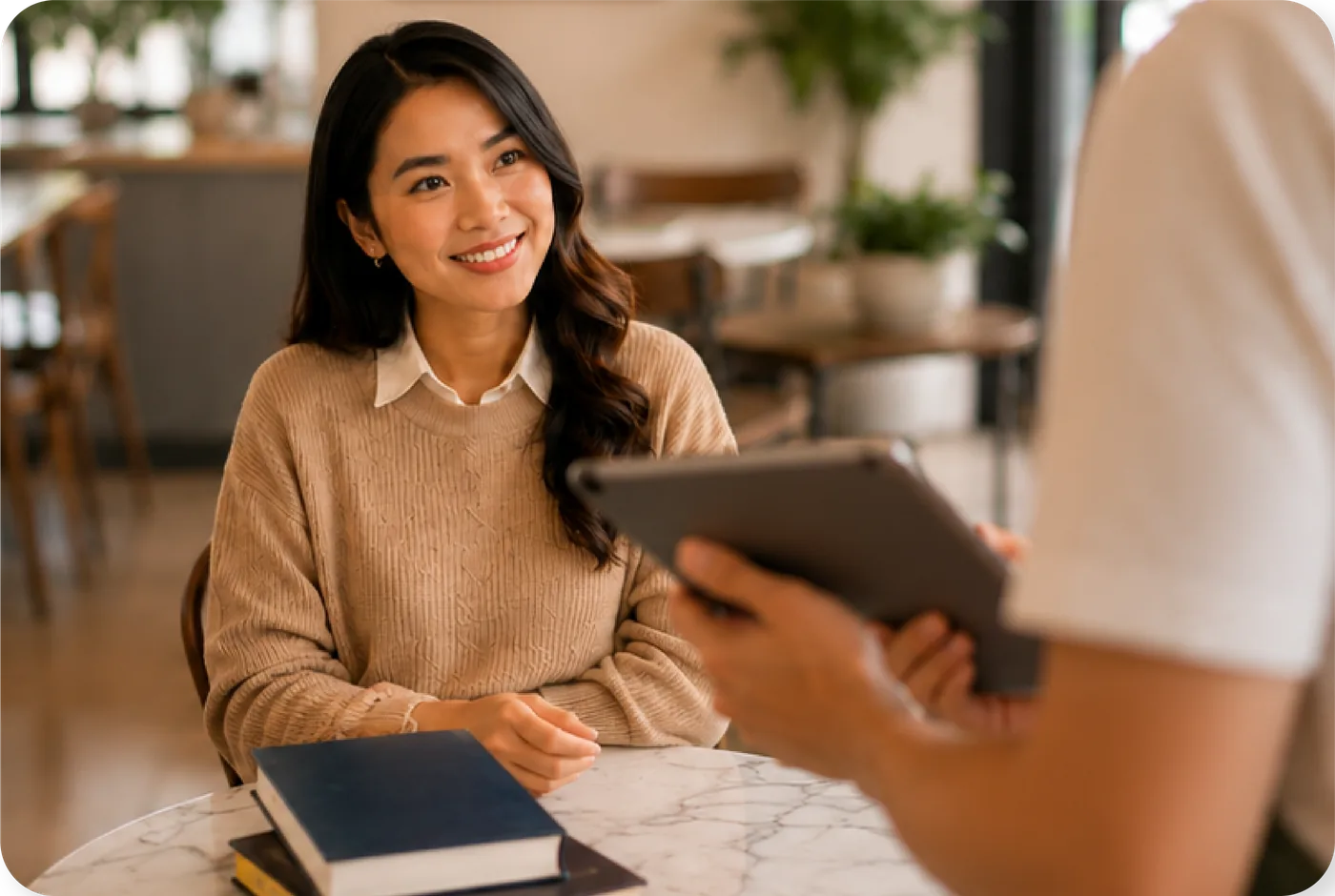 The guest smiles at the counter while the cashier reviews her profile on a tablet
